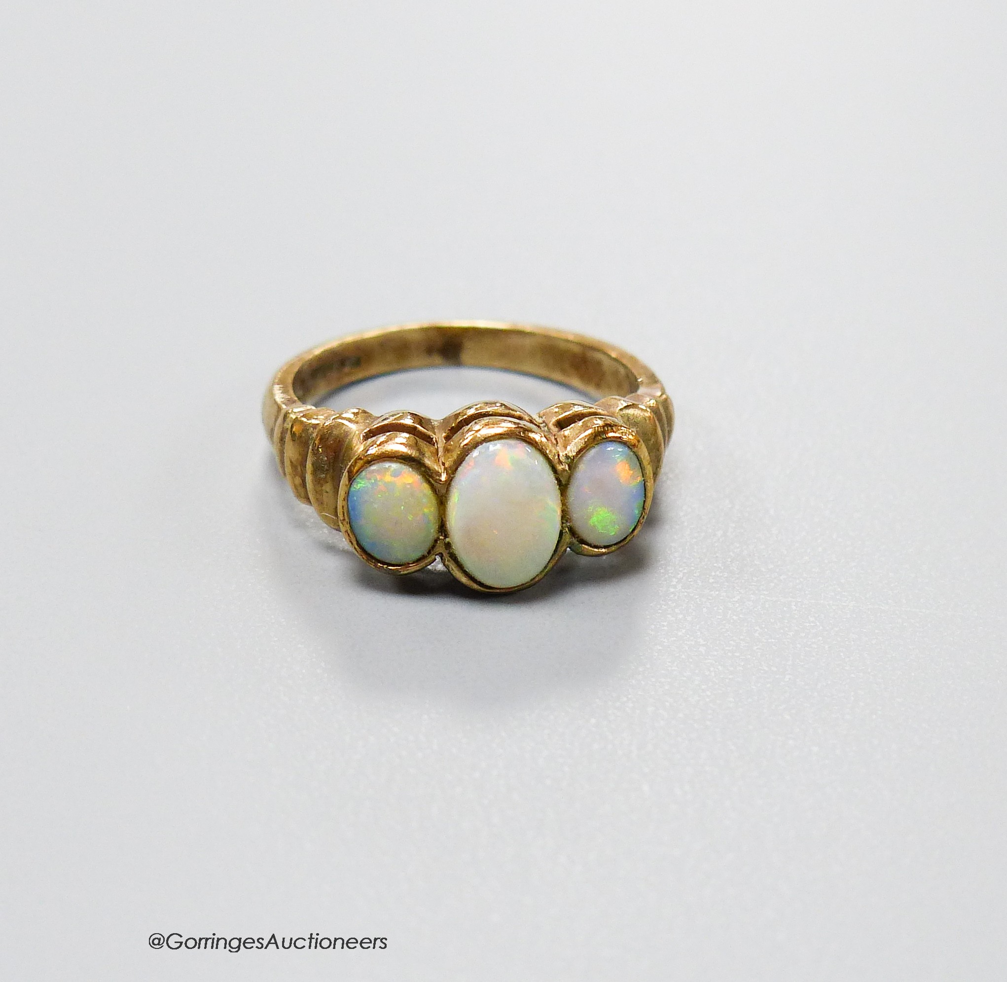 A 9ct gold and three stone white opal set half hoop ring, with ribbed shoulders, size K, gross 3.5 grams.
